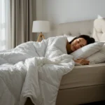Woman sleeping peacefully under a soft white bamboo duvet in a bright, cozy bedroom.